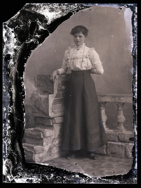 Rechtstaande jonge vrouw met lange rok, opgesmukte blouse, lange halsketting, Melle, 1910-1920