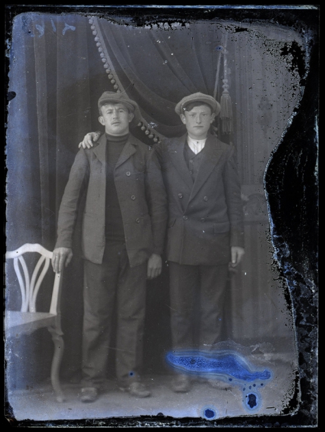 Staand portret van 2 jonge mannen in kostuum en hoofddeksel, 1 in wit hemd zonder opstaande boord en 1 in donkere pullover, Melle , 1910-1920