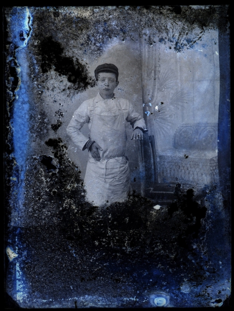 Staand portret van jongen in bakkersschort en donkere pet, Melle, 1910-1920
