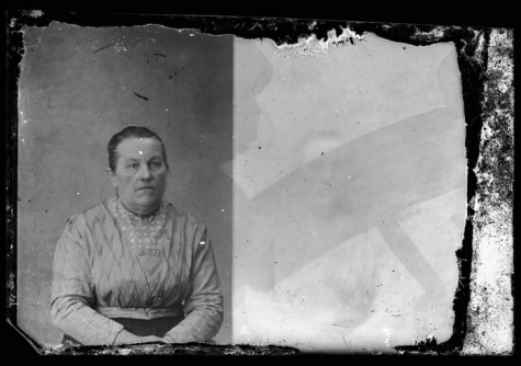 Zittend portret van vrouw in feestkledij, versierde bloes en korte halsketting, strak naar achter gekamd opgestoken haar, Melle, 1910-1920