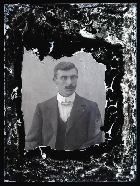 Portret van man in feestkledij bestaande uit kostuum, wit hemd en vlinderdas, gemodelleerde snor en golvend naar achter gekamd haar , Melle, 1910-1920