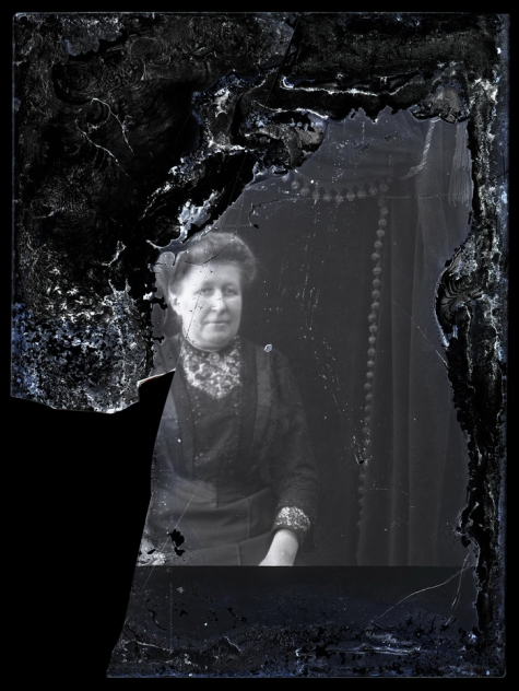 Zittende foto van vrouw in feestkledij en golvend opgestoken haar, Melle, 1910-1920