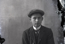 Zittend portret van jonge man in kostuum met wit hemd en stropdas, hoofddeksel, Melle , 1910-1920