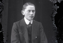 Zittend portret jonge man in feestkledij, bestaande uit kostuum en opgezette witte hemdskraag met stropdas, Melle , 1910-1920