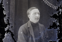 Zittend portret man van middelbare leeftijd met vest en gestreepte pullover met hoge kraag, strak opzijgekamd haar, Melle , 1910-1920