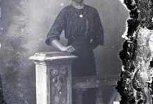 Staand portret van jonge vrouw in feestkledij met driekwart mouwen en witte opgezette halsboord, halsketting, Melle , 1910-1920