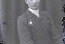 Zittend portret van jonge man in feestkledij bestaande uit kostuum, wit hemd en stropdas, kuifvormig naar achter gekamd haar, Melle, 1910-1920
